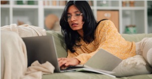 Woman relaxed on a couch, working on a laptop.