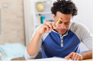Young adult holding a pencil, working through a notebook.